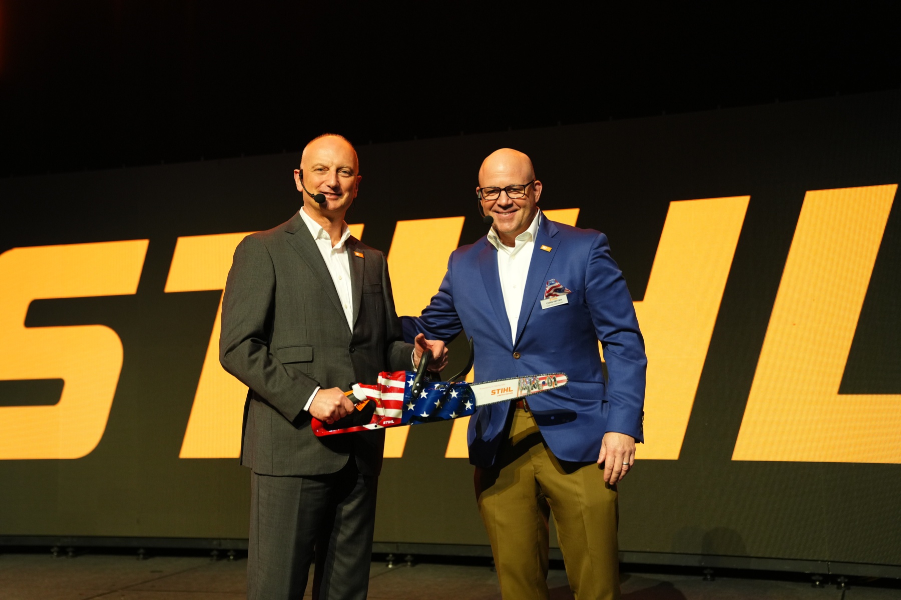 Nikolas Stihl (à gauche) et Chris Keffer, directeur général de STIHL Inc. aux États-Unis, présentent une scie anniversaire avec un drapeau américain.